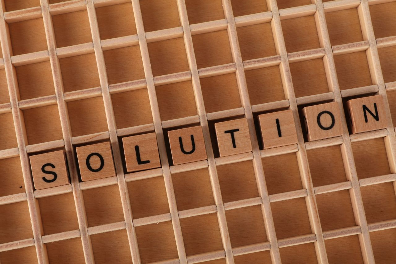 Word tiles spelling 'solution' on a wooden grid background for business concept.